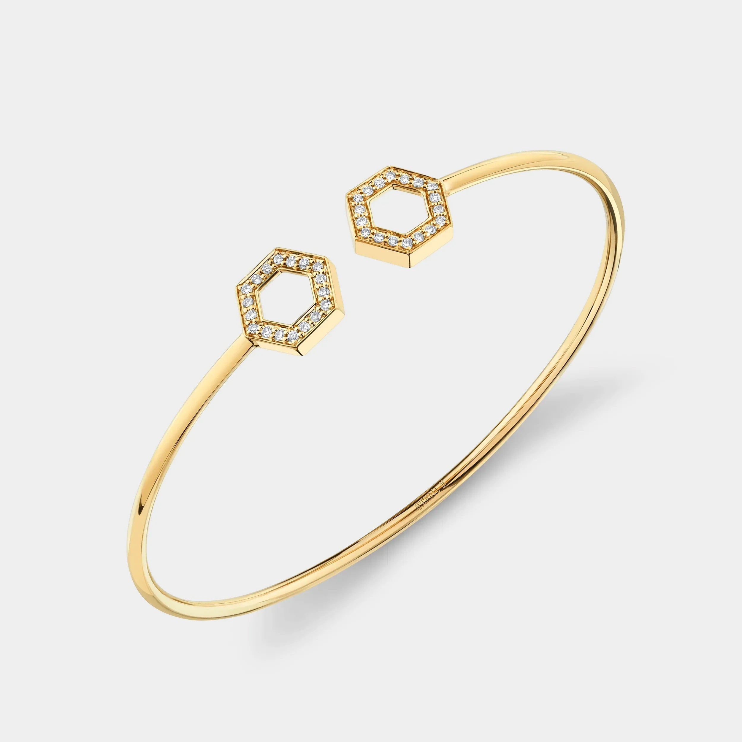 Yellow gold cuff bracelet with diamond hexagon accents on grey background