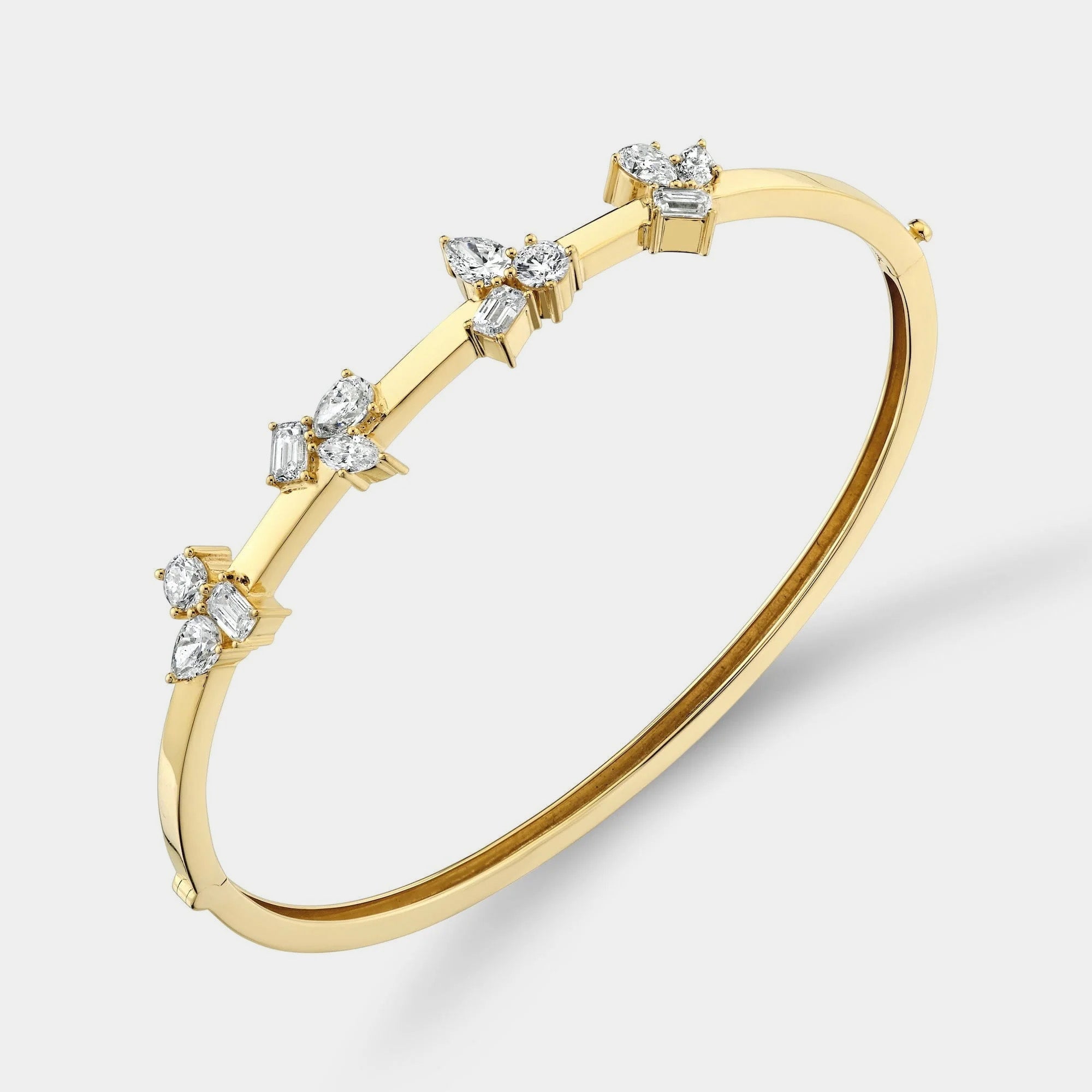 Yellow gold diamond bangle bracelet on grey background, side angle view