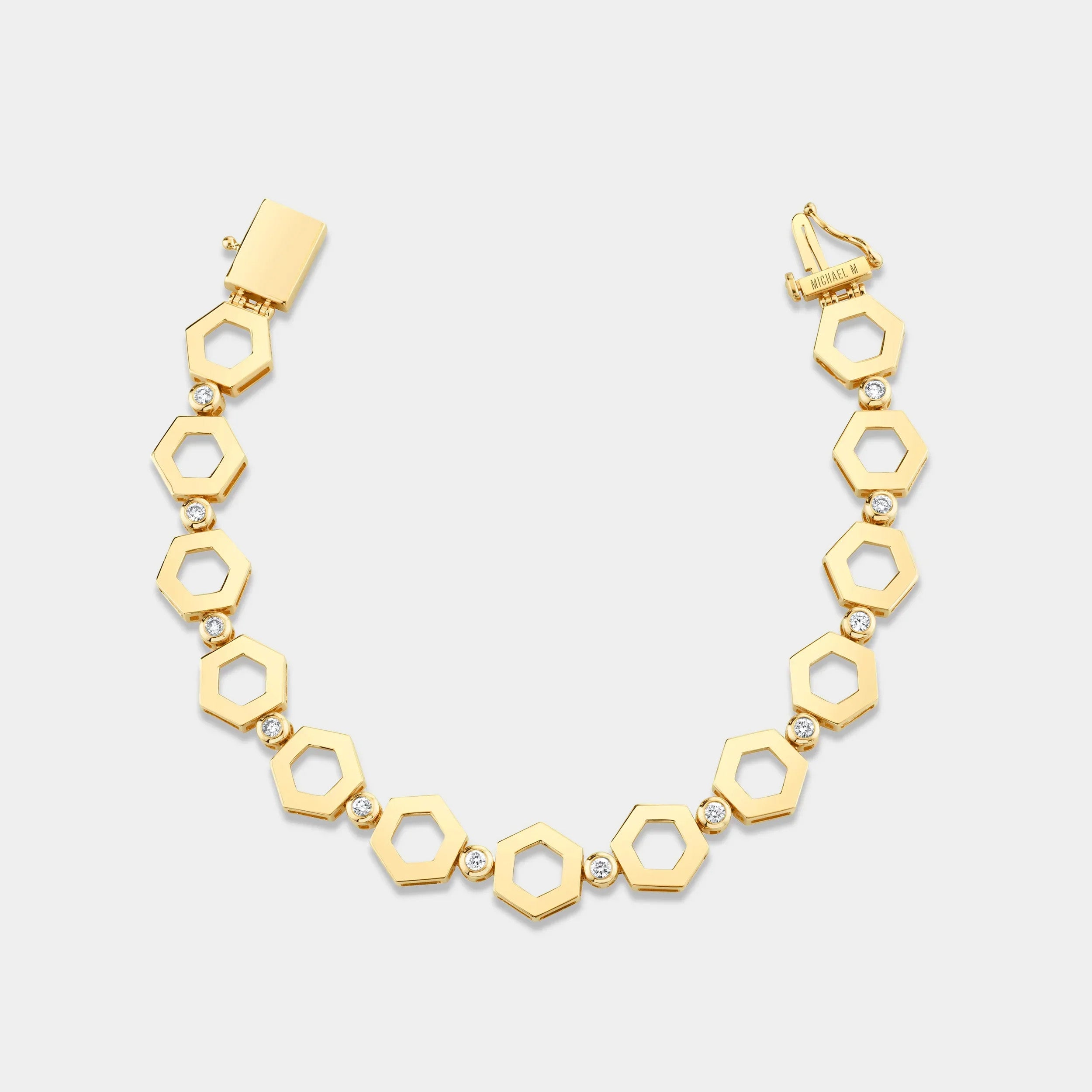Yellow gold diamond link bracelet with hexagon shaped links on grey background, flat lay view