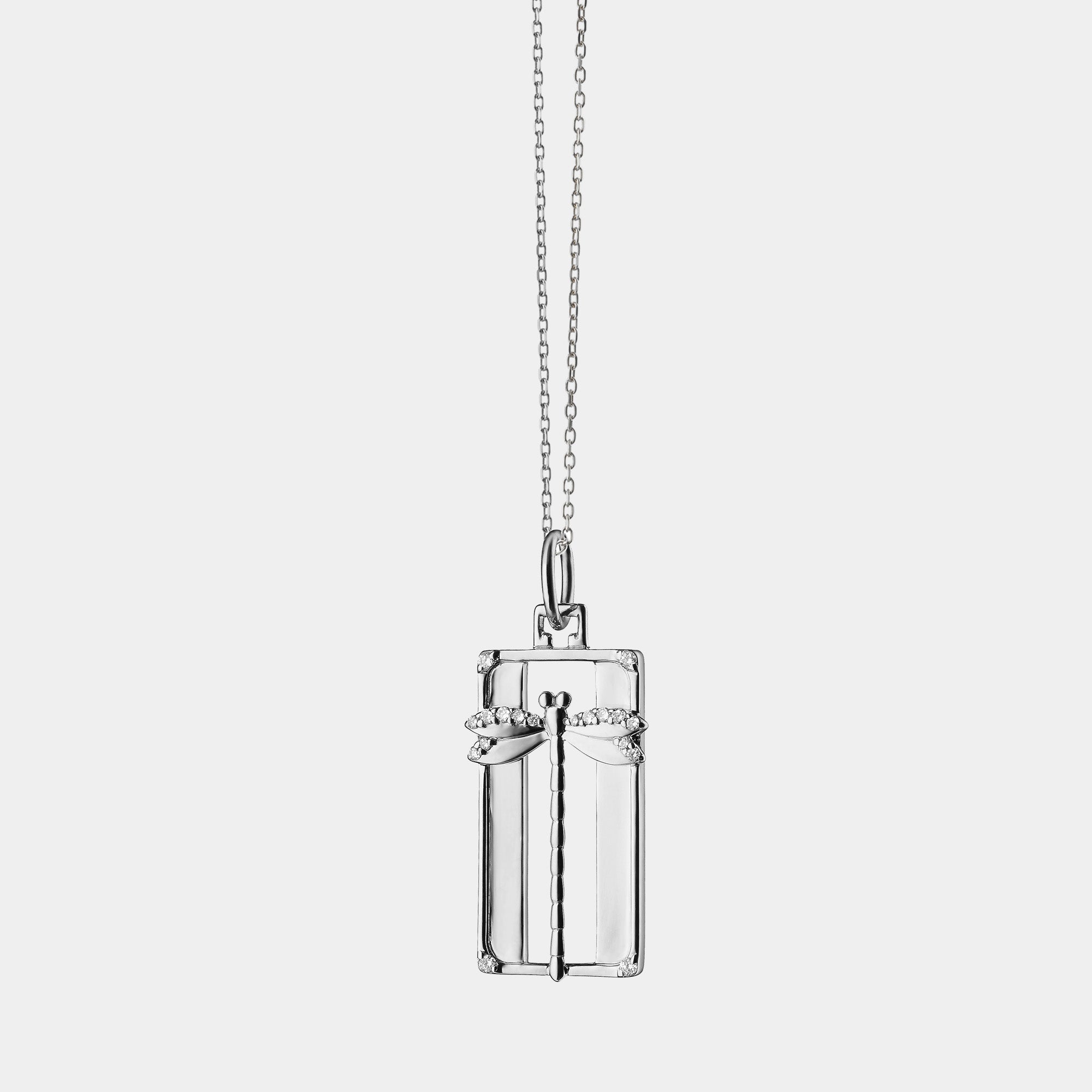 Silver dragonfly  pendant on a chain against a grey background