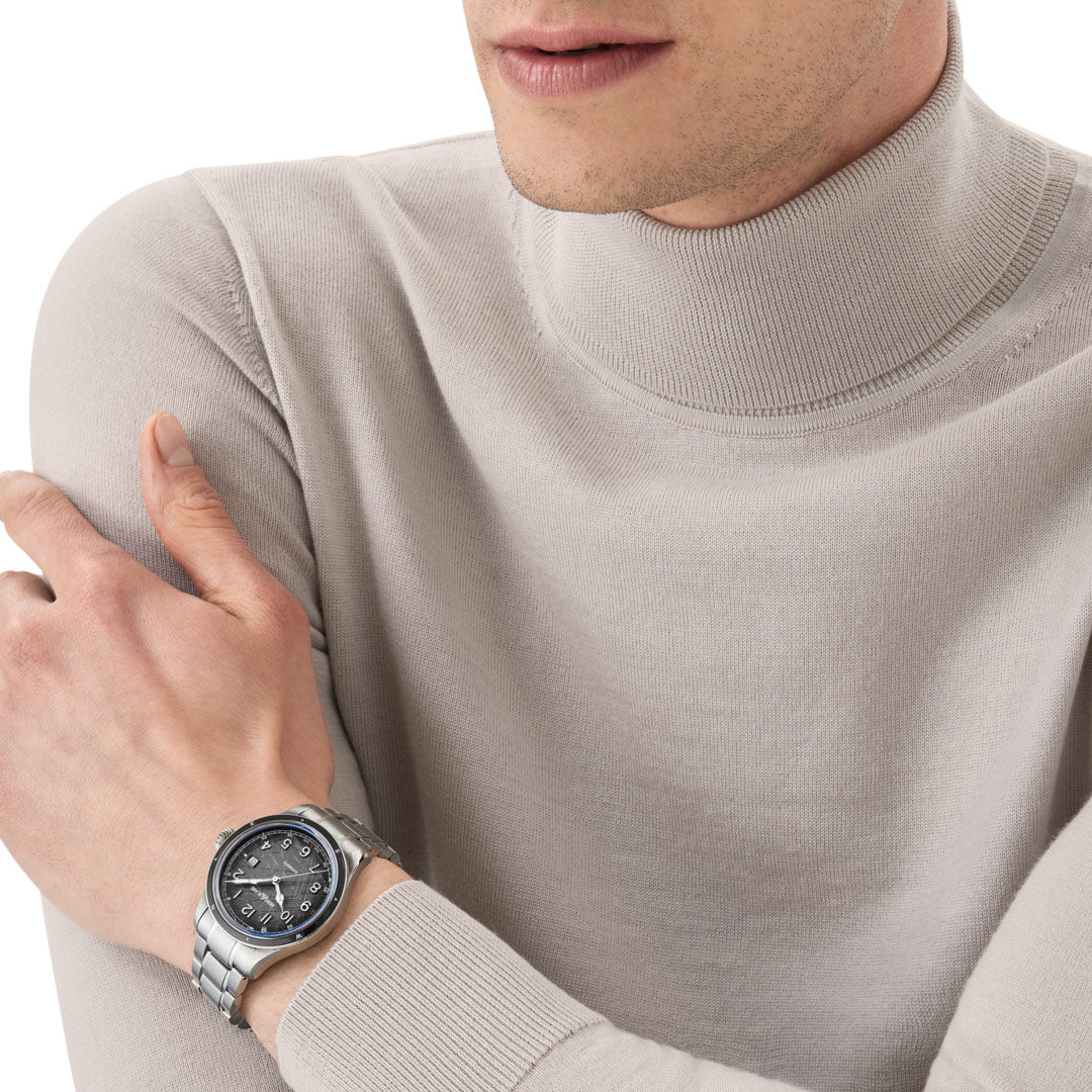 Person wearing a silver watch on a plain background
