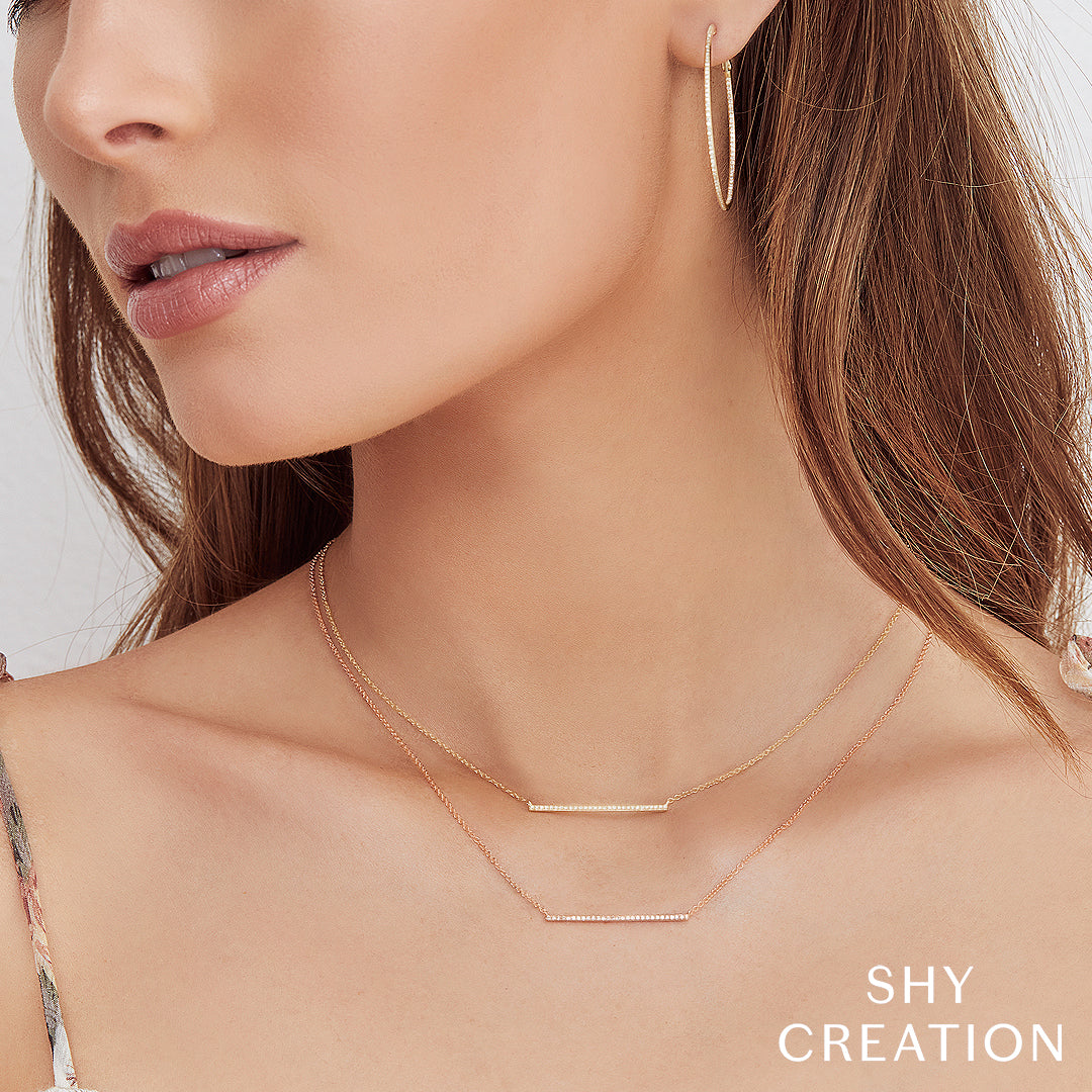 Close-up of a woman wearing gold bar necklace.