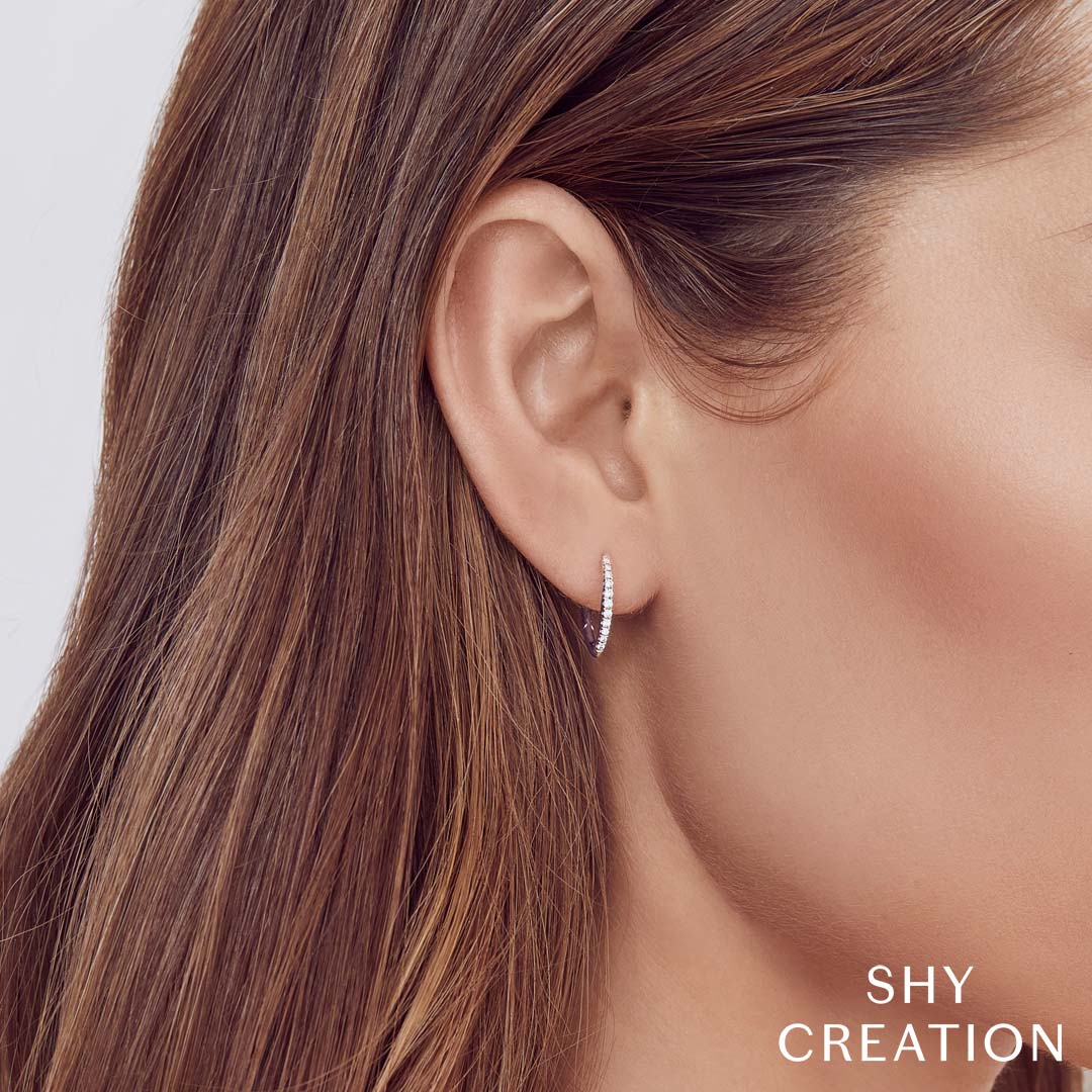 Woman wearing white gold diamond hoop earrings, closeup angle