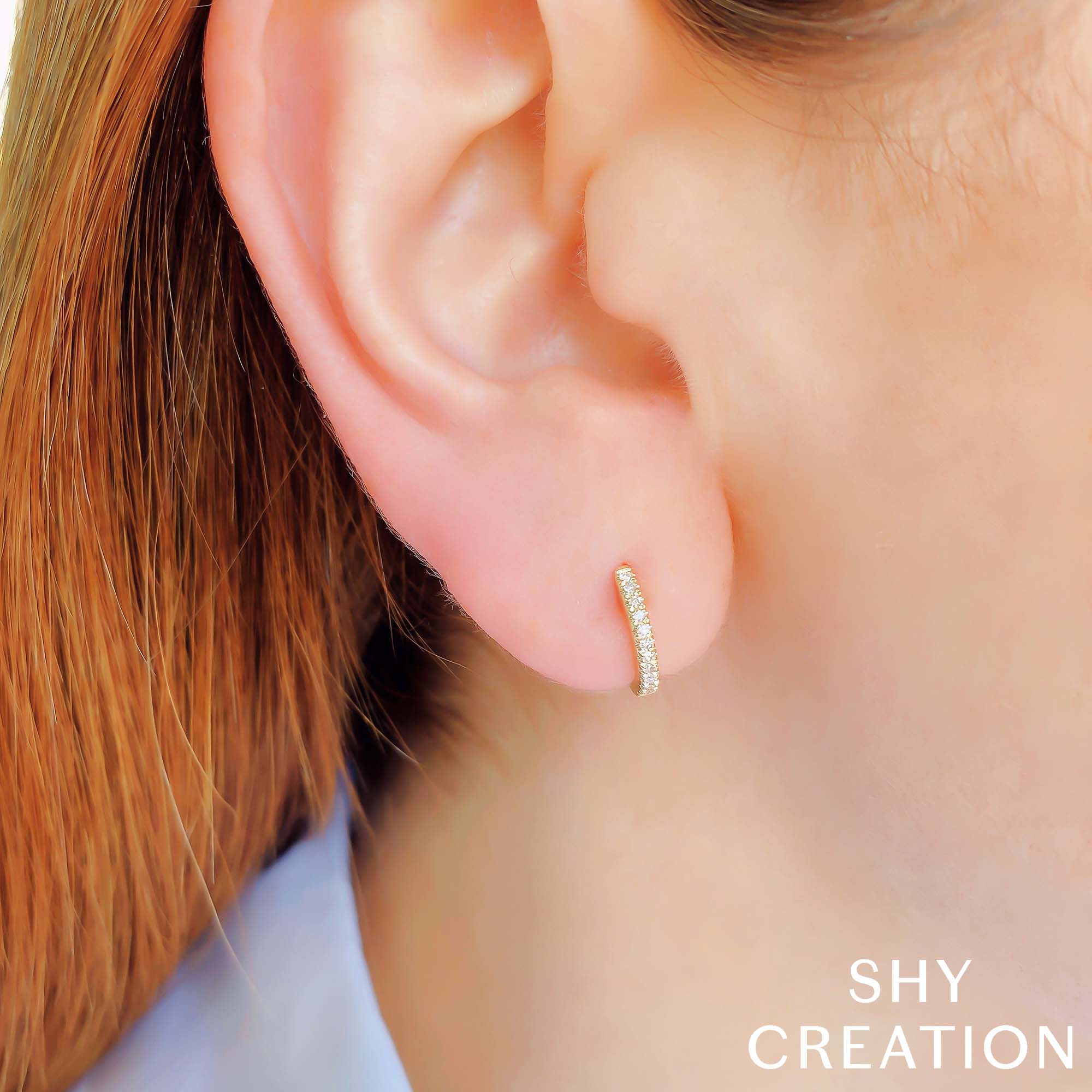 Woman wearing yellow gold diamond huggie earring