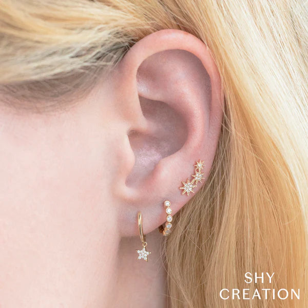 Woman wearing yellow gold diamond star huggie earrings, closeup ear view