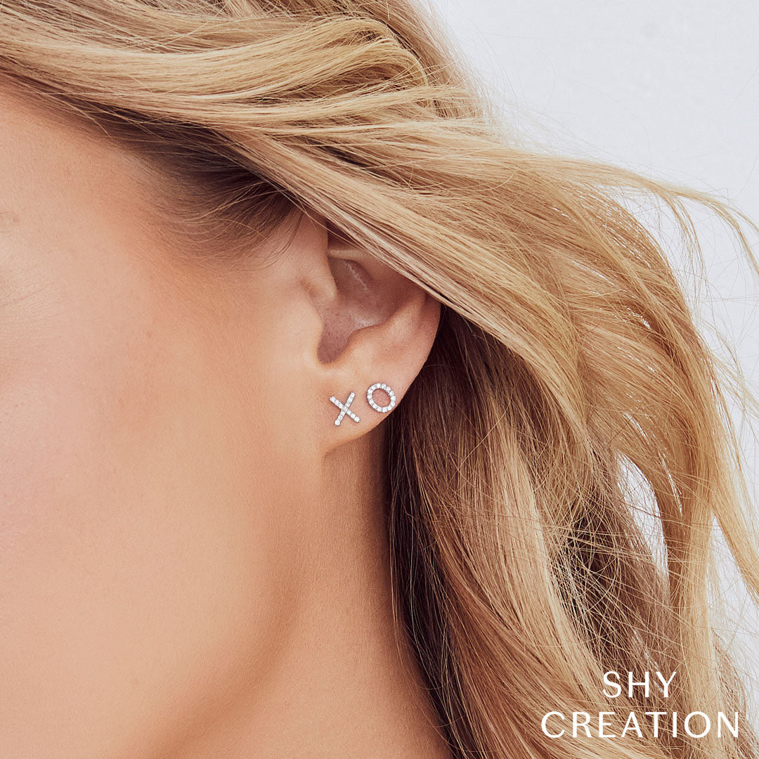 Woman wearing white gold "xo" diamond stud earrings