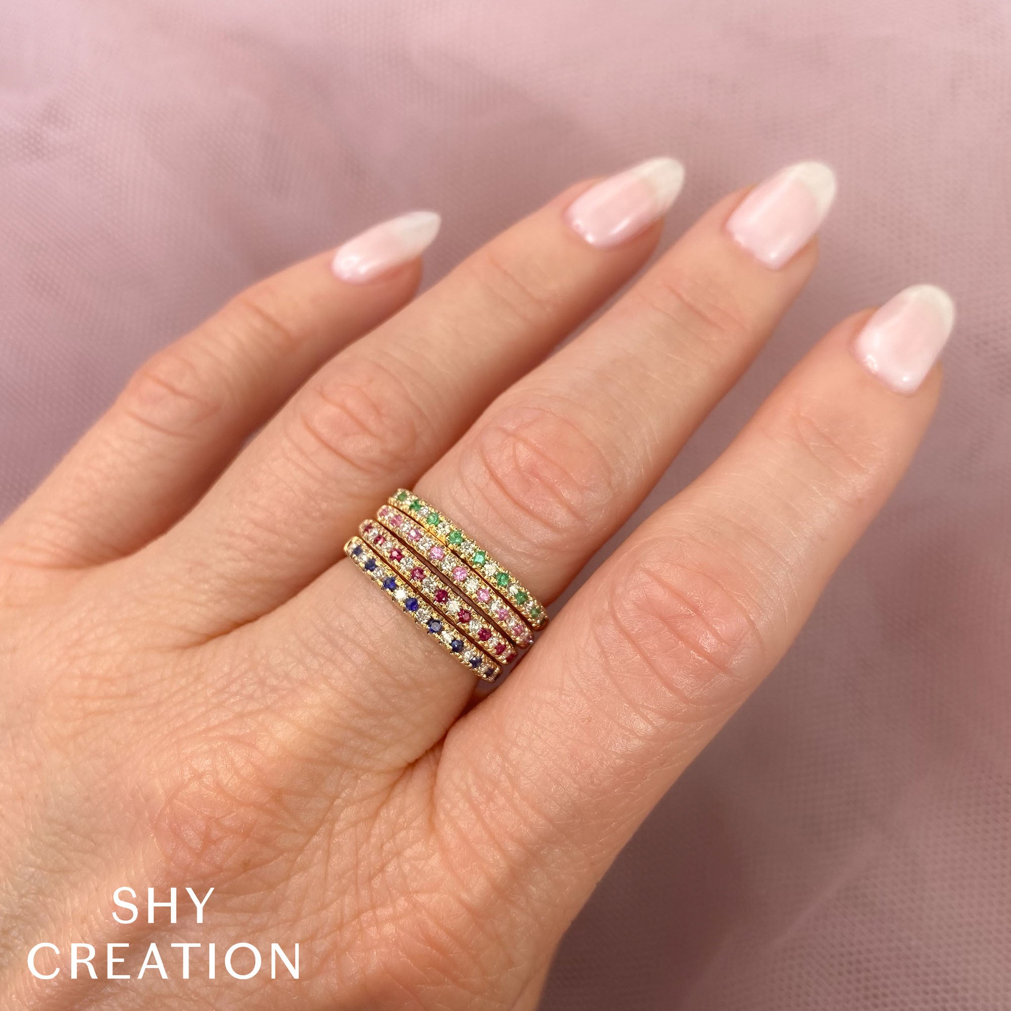 Woman wearing yellow gold emerald and diamond stacking ring