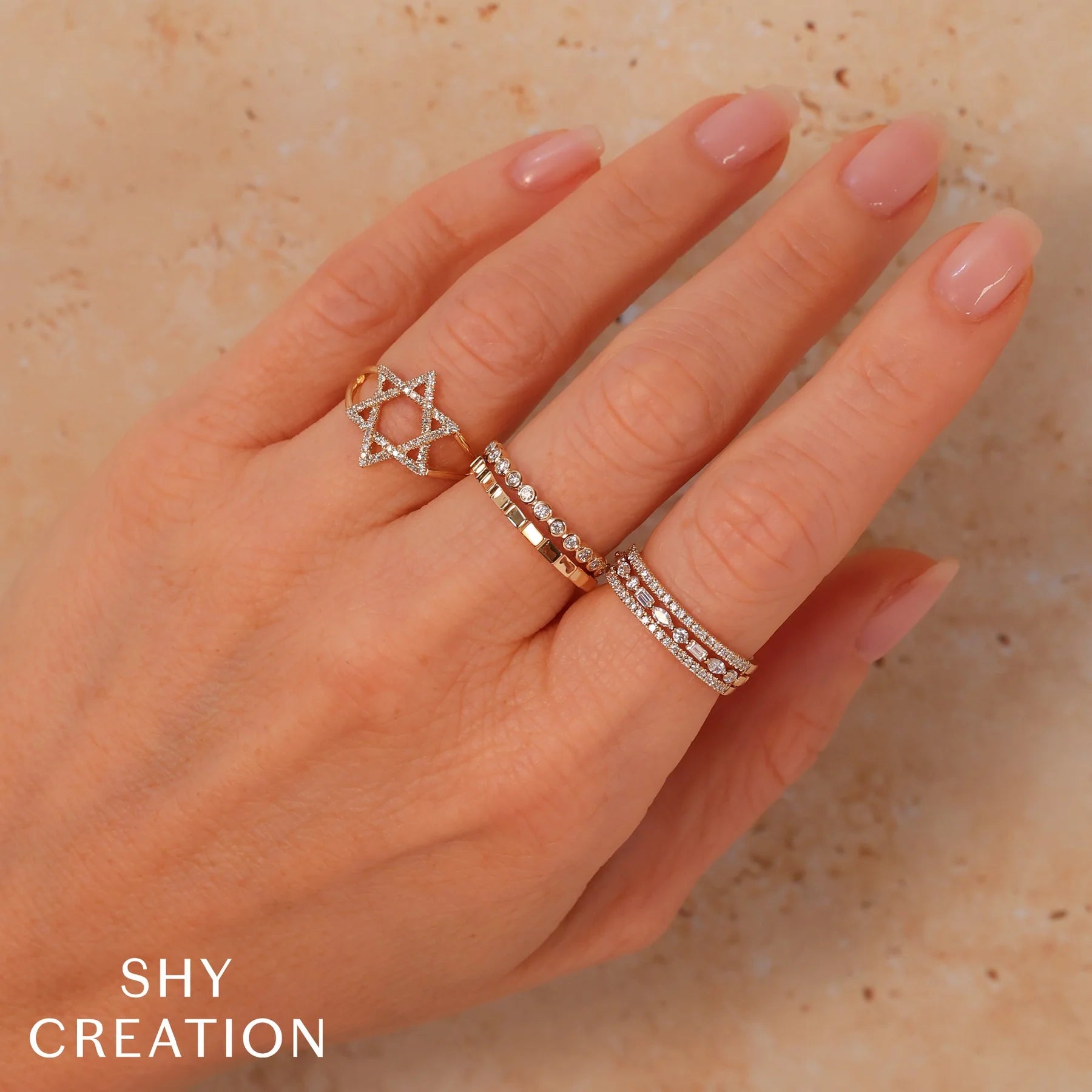 Woman's hand wearing yellow gold, mixed diamond shapes three row stacking fashion ring