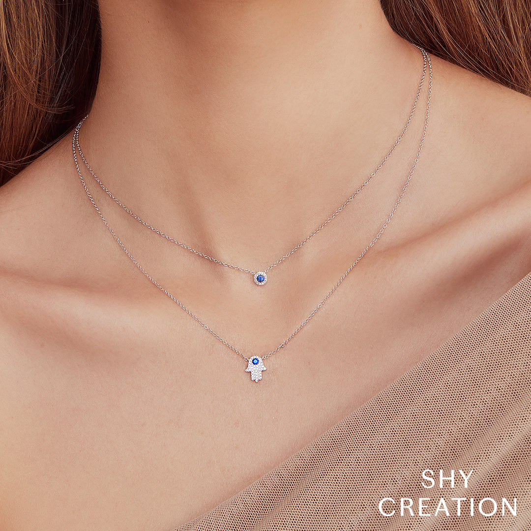 Women wearing white gold necklace with a blue sapphire pendant on a white background