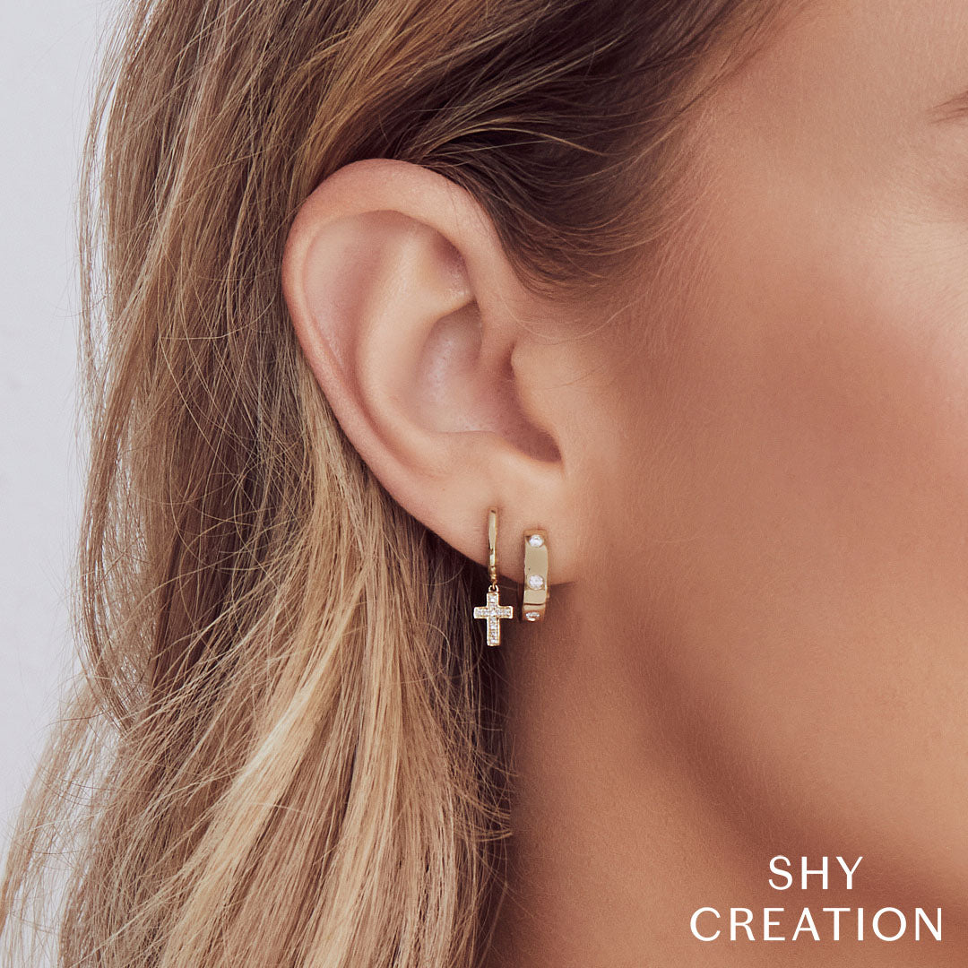 Closeup of woman wearing yellow gold bezel set diamond huggie earrings