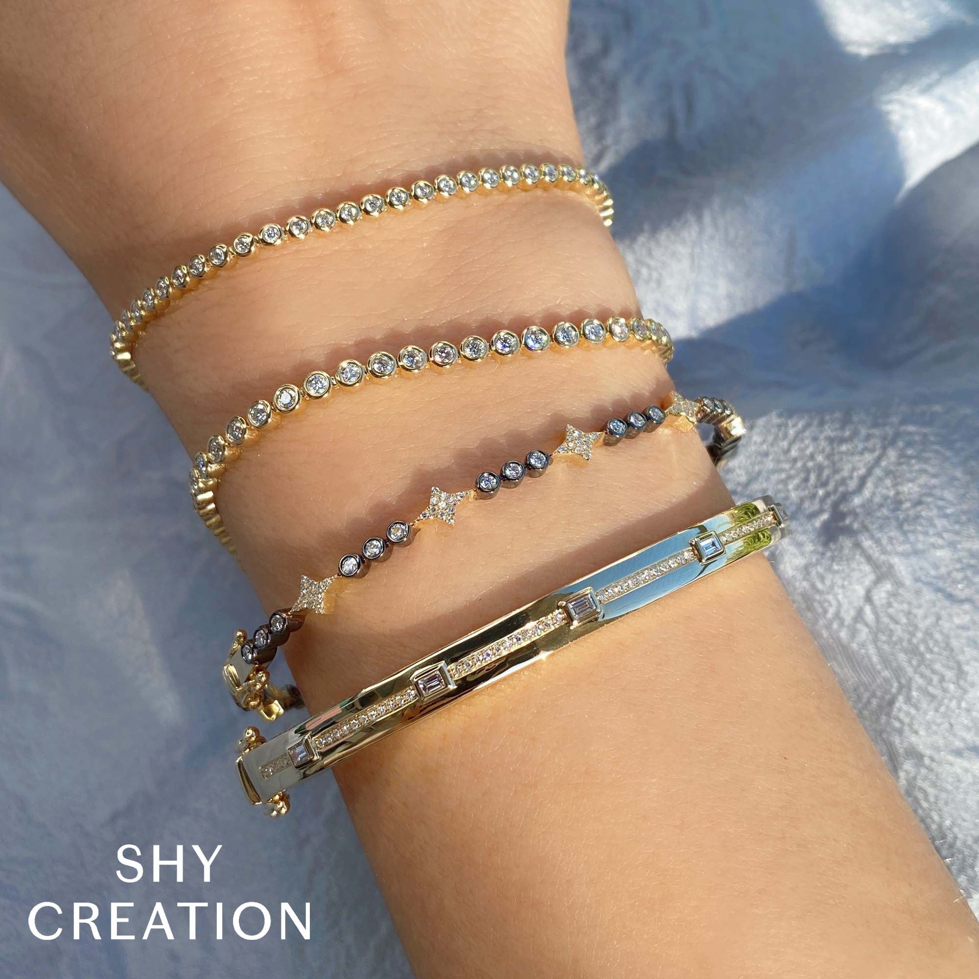 Woman wearing yellow gold bezel set diamond tennis bracelet, closeup of wrist