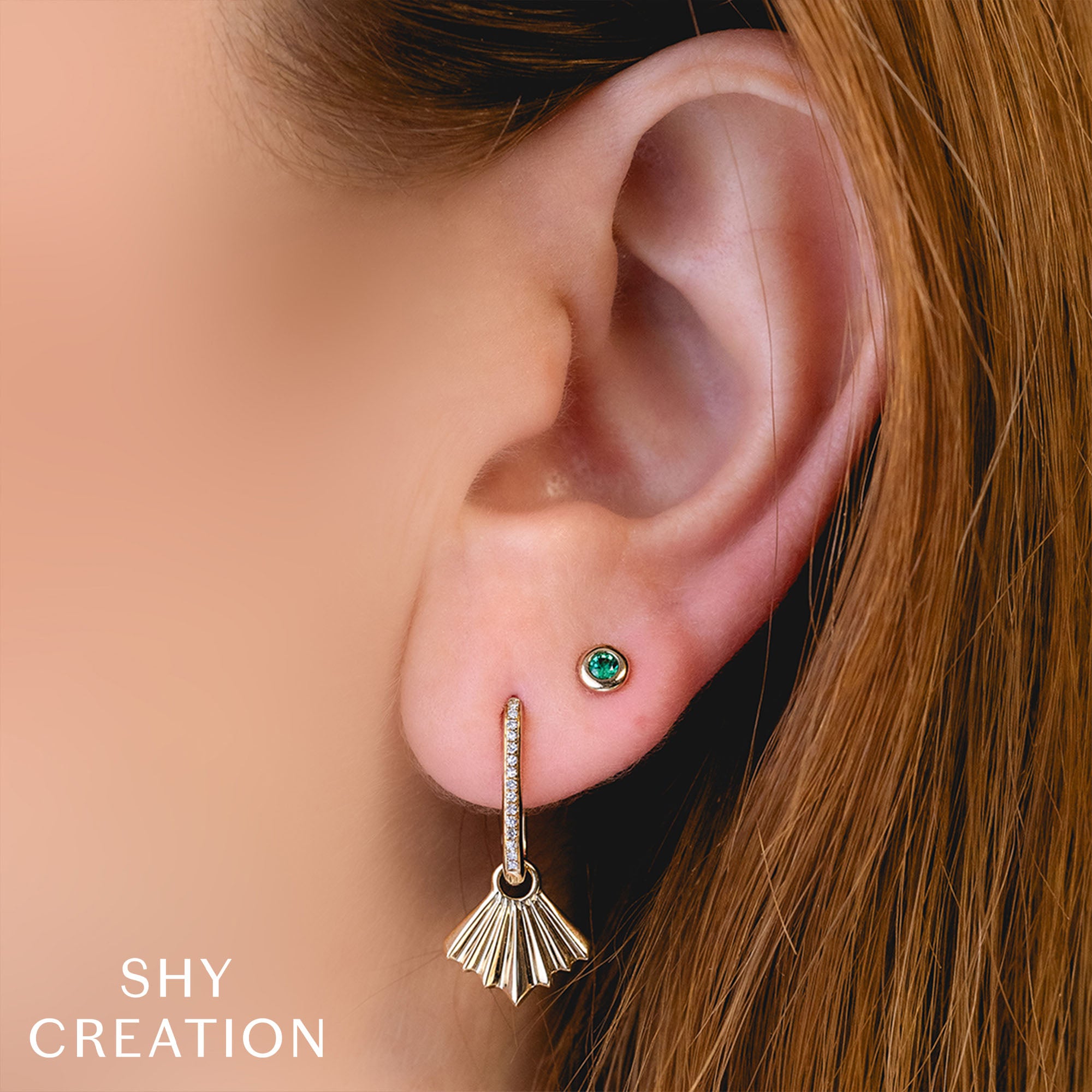 Woman wearing, yellow gold bezel set emerald stud earrings
