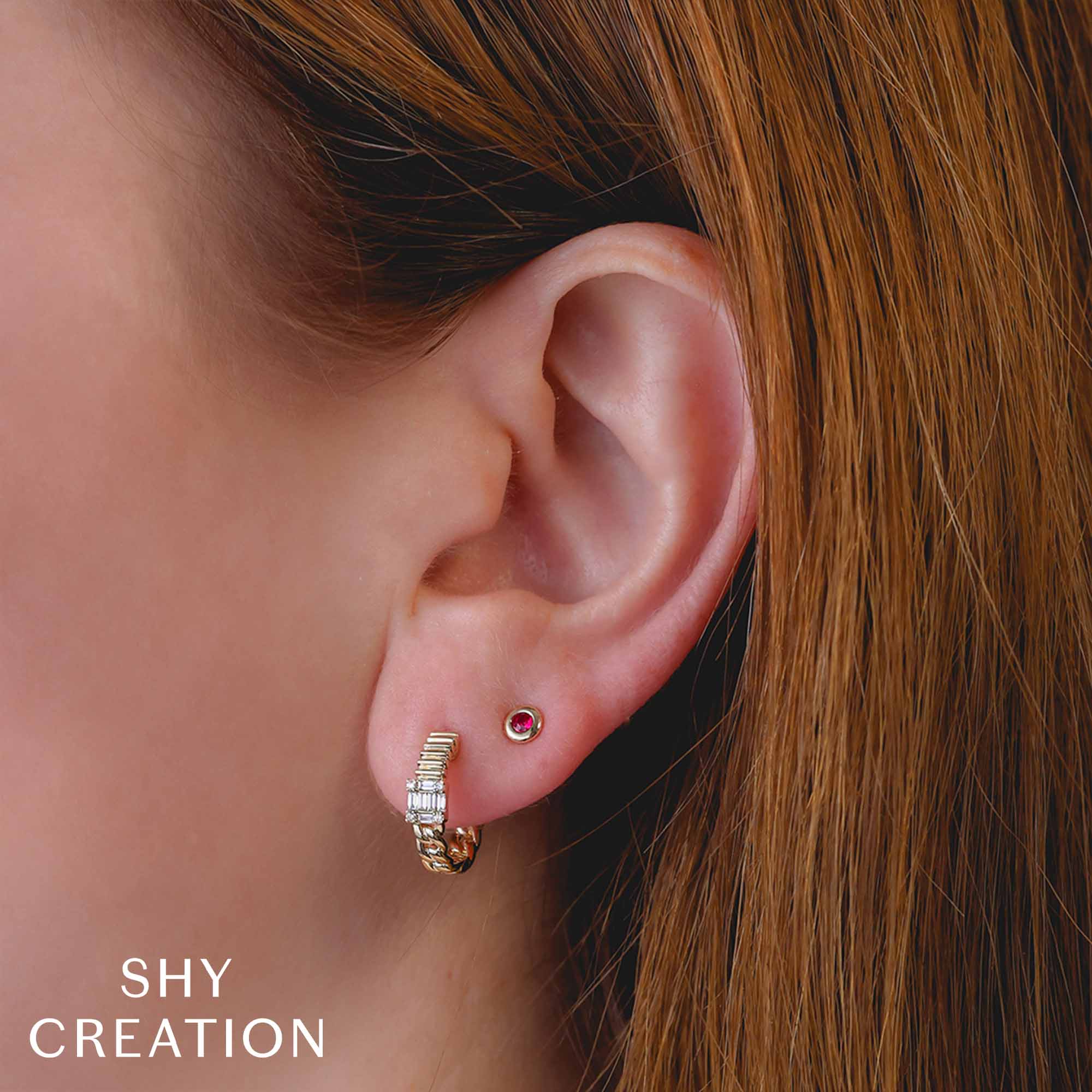 Woman wearing yellow gold bezel set ruby stud earrings