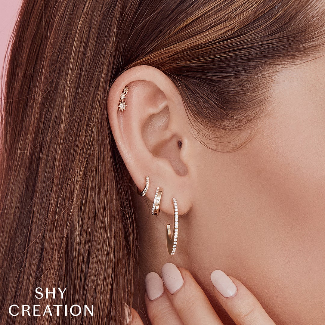 Woman wearing yellow gold diamond huggie earrings