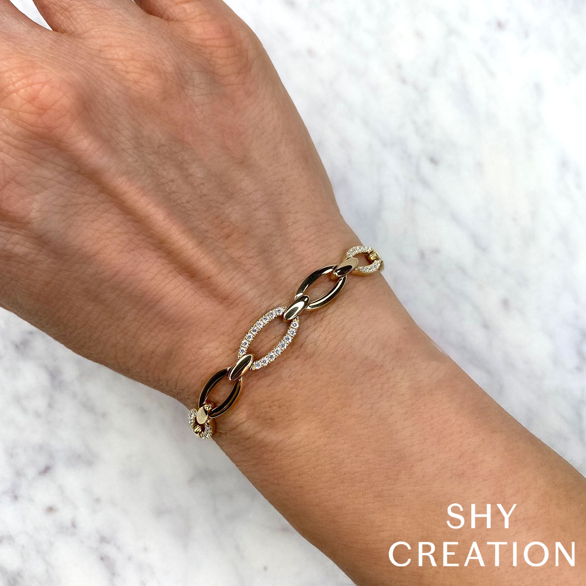 Woman wearing yellow gold diamond link bracelet, wrist closeup