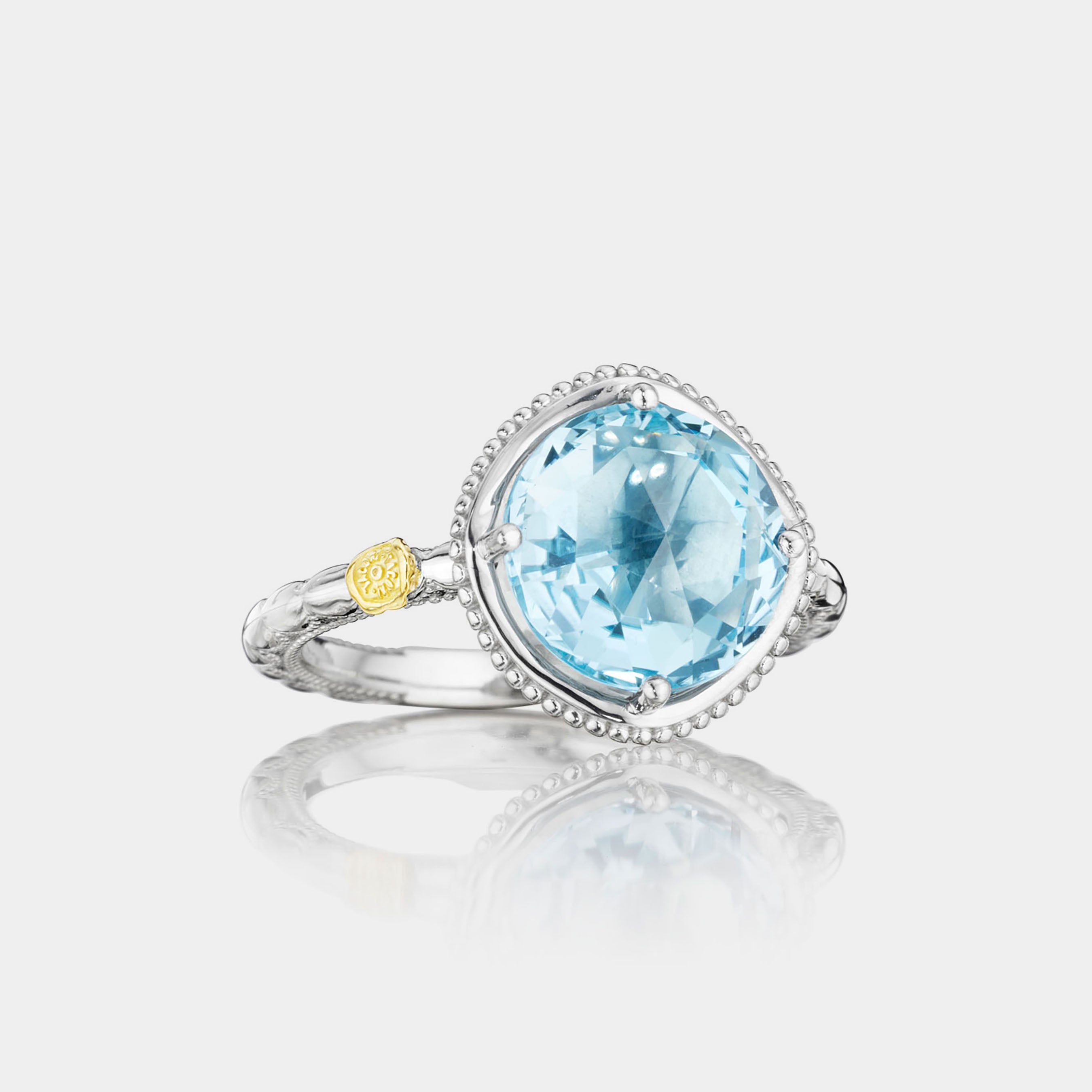 Sterling Silver and White Gold Round Blue Topaz Ring on grey background.
