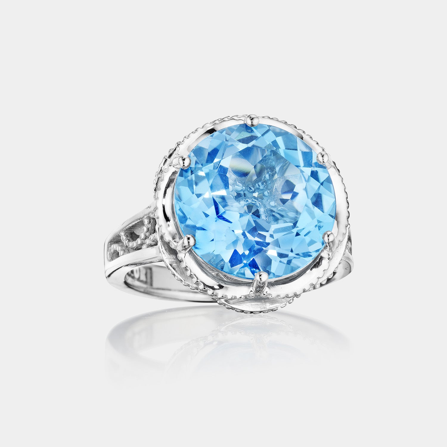 Sterling Silver and White Gold Round Swiss Blue Topaz Ring on grey background.