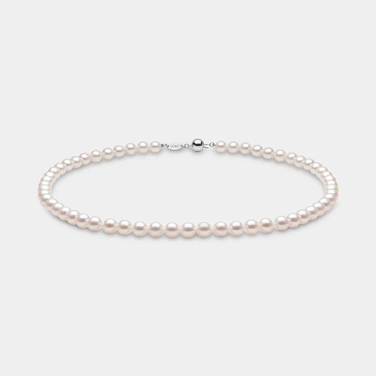Classic akoya pearl strand necklace on  grey background with white gold clasp