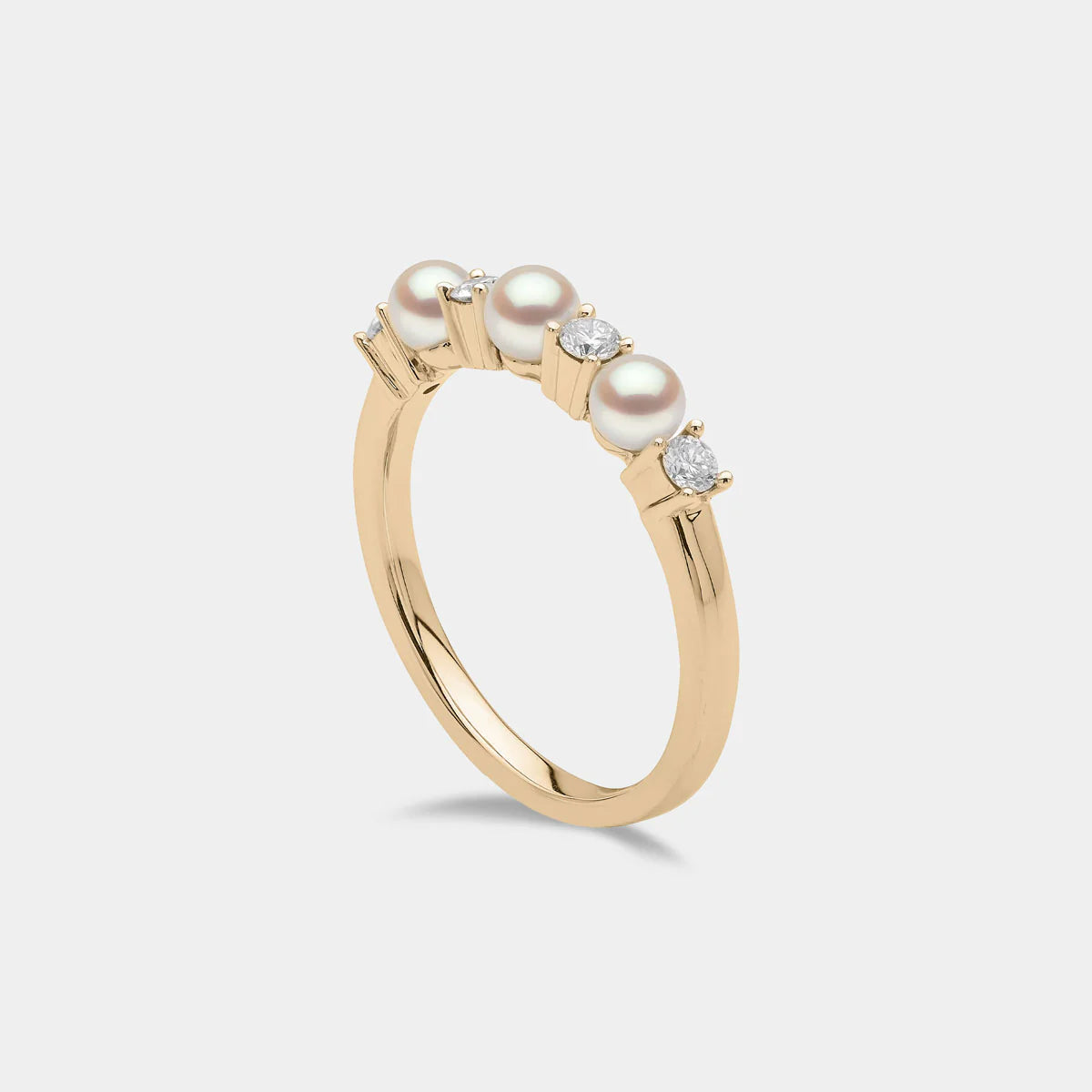 Yellow gold pearl and diamond ring on grey background, side angle view