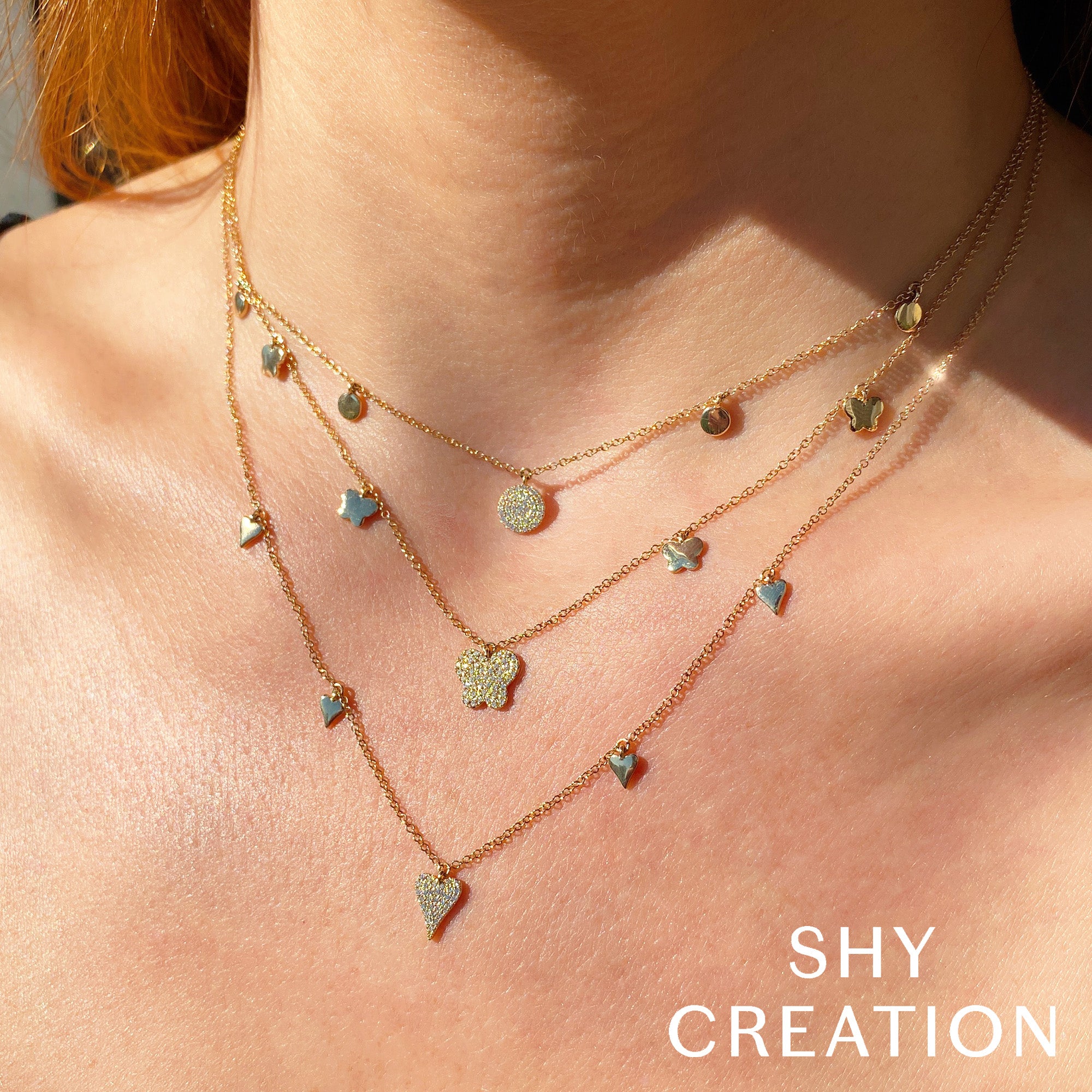 Woman wearing yellow gold necklace with heart-shaped pendants, front view